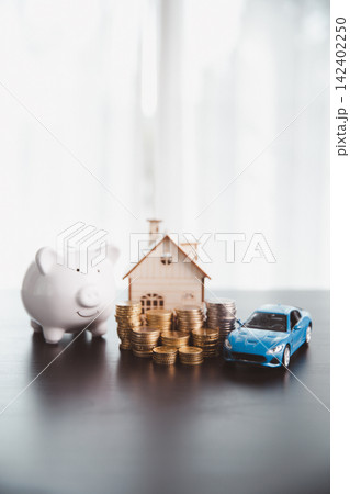Piggy bank, wooden house, coin stacks, and blue car model symbolize balanced savings for home and vehicle ownership, household budgeting, asset building, financial security, and future goals. Piggy bank, wooden house, coin stacks, and blue car model symbolize balanced savings for home and vehicle ownership, household budgeting, asset building, financial security, and future goals. 142402250