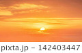 Sunset with orange sky and glowing sun over clouds 142403447