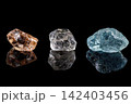 Three colorful gemstones on black reflective surface 142403456