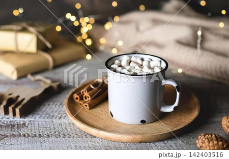 White mug with hot chocolate and marshmallows on wooden tray White mug with hot chocolate and marshmallows on wooden tray 142403516
