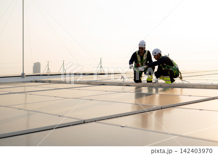 Two engineer inspecting solar panel on roof of building, team man worker or technician. Two engineer inspecting solar panel on roof of building, team man worker or technician. 142403970