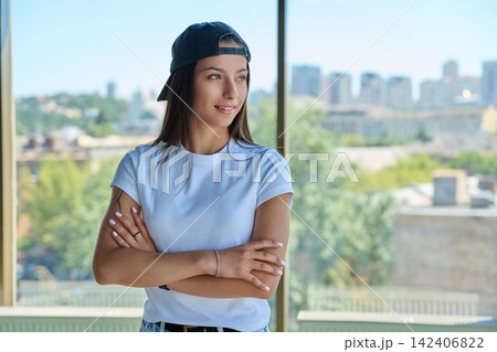 Young woman in cap looking away near panoramic window portrait Young woman in cap looking away near panoramic window portrait 142406822