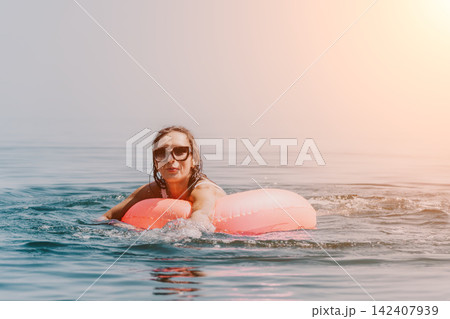 Woman floating inflatable tube, happy vacation fun on sparkling turquoise ocean water background Woman floating inflatable tube, happy vacation fun on sparkling turquoise ocean water background 142407939
