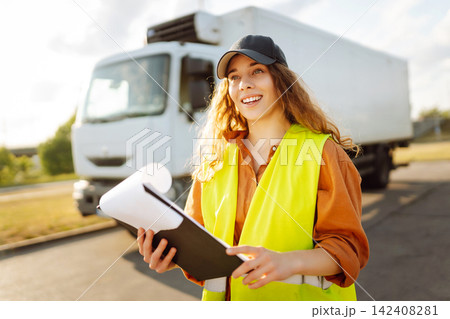 Young woman professional driver checking shipment list on a -parking lot. Transportation concept. Young woman professional driver checking shipment list on a -parking lot. Transportation concept. 142408281