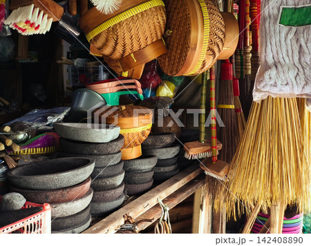 Traditional Indonesian handmade crafts and wooden kitchenware displayed for sale at Pasar Kotagede market in Yogyakarta, featuring woven bamboo goods, clay pottery, stone mortars, and household cleani Traditional Indonesian handmade crafts and wooden kitchenware displayed for sale at Pasar Kotagede market in Yogyakarta, featuring woven bamboo goods, clay pottery, stone mortars, and household cleani 142408890