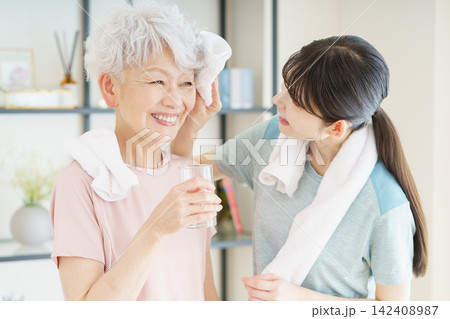 タオルでシニア日本人女性の汗を拭く若い日本人介護士 タオルでシニア日本人女性の汗を拭く若い日本人介護士 142408987