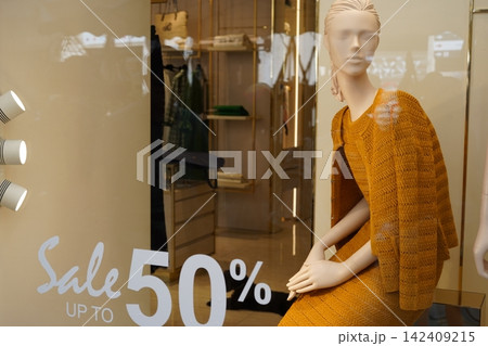 Fashion Mannequin Wearing Mustard Knit Outfit Behind Store Window Sale 142409215