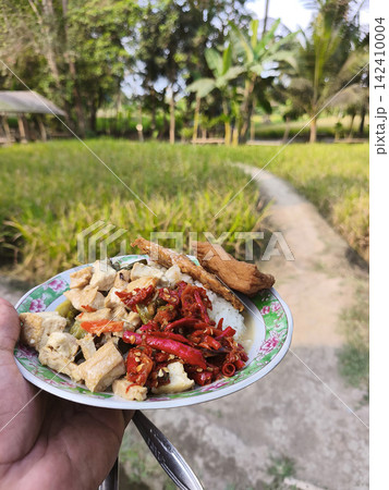 Top down overhead view of traditional Javanese food spread including rice, crispy fried egg, sambal, and side dishes served on a wooden table at Warung Kopi Klotok in Yogyakarta, Indonesia. Top down overhead view of traditional Javanese food spread including rice, crispy fried egg, sambal, and side dishes served on a wooden table at Warung Kopi Klotok in Yogyakarta, Indonesia. 142410004