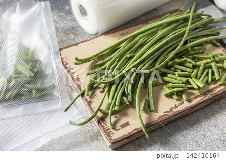 Vacuum sealed fresh green beans in packaging on a light grey background, healthy eating, zero waste, meal prep concept. Vacuum sealed fresh green beans in packaging on a light grey background, healthy eating, zero waste, meal prep concept. 142410164