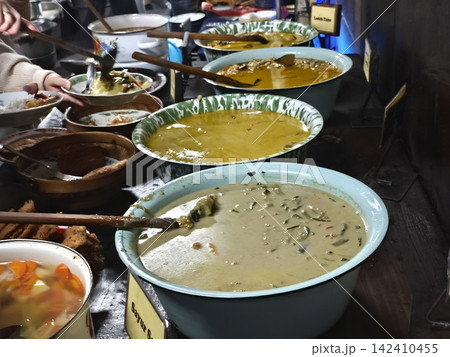 Various traditional Javanese food dishes and curries served in clay bowls at a local Indonesian warung buffet in Yogyakarta. Various traditional Javanese food dishes and curries served in clay bowls at a local Indonesian warung buffet in Yogyakarta. 142410455