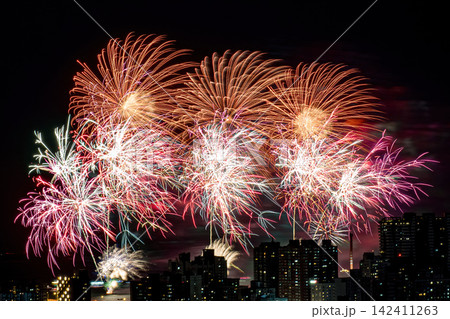 Spectacular colorful fireworks illuminating the night sky above a dense city skyline during a festive celebration. Spectacular colorful fireworks illuminating the night sky above a dense city skyline during a festive celebration. 142411263