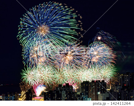 Spectacular colorful fireworks illuminating the night sky above a dense city skyline during a festive celebration. 142411264