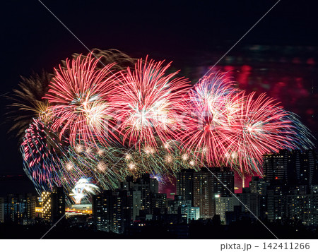 Spectacular colorful fireworks illuminating the night sky above a dense city skyline during a festive celebration. Spectacular colorful fireworks illuminating the night sky above a dense city skyline during a festive celebration. 142411266