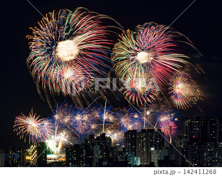 Spectacular colorful fireworks illuminating the night sky above a dense city skyline during a festive celebration. Spectacular colorful fireworks illuminating the night sky above a dense city skyline during a festive celebration. 142411268