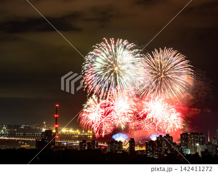 Spectacular colorful fireworks illuminating the night sky above a dense city skyline during a festive celebration. Spectacular colorful fireworks illuminating the night sky above a dense city skyline during a festive celebration. 142411272