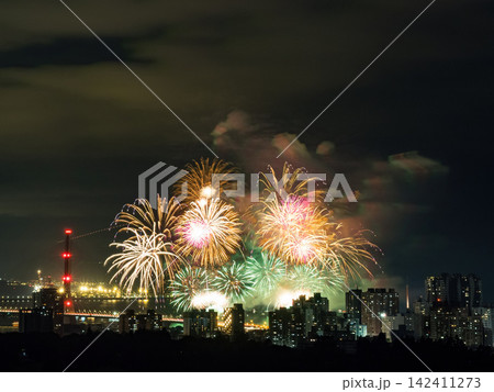 Spectacular colorful fireworks illuminating the night sky above a dense city skyline during a festive celebration. 142411273