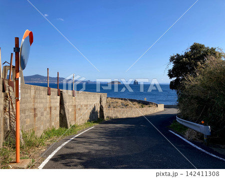 池島の青い海へ向かって下る細い海岸道路 142411308