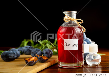 Homemade fruit syrup with blue plums on wooden background Homemade fruit syrup with blue plums on wooden background 142412433