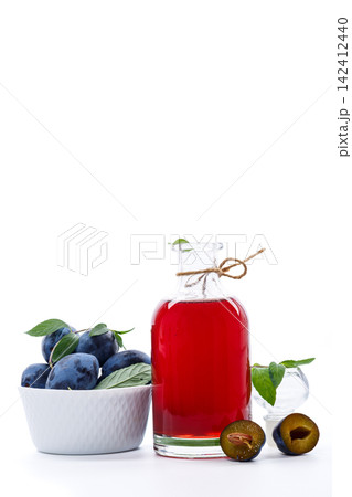 Plum fruit syrup in glass bottle on bright white background Plum fruit syrup in glass bottle on bright white background 142412440