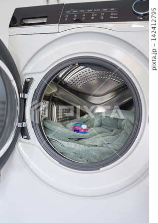Laundry detergent pod placed on towel inside open front loading washing machine Laundry detergent pod placed on towel inside open front loading washing machine 142412795