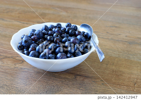 Tasty Raw Blueberries and Forest Bilberries in White Dish on Wooden Countertop Tasty Raw Blueberries and Forest Bilberries in White Dish on Wooden Countertop 142412947