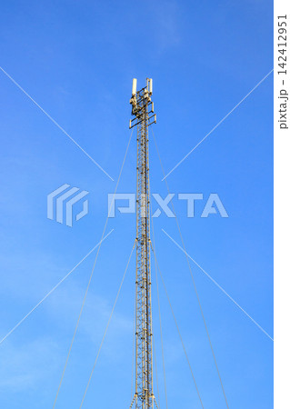 High Telecommunication Mast Supported by Guy Wires Against Clear Blue Sky High Telecommunication Mast Supported by Guy Wires Against Clear Blue Sky 142412951