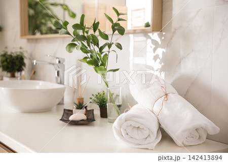 Towels and green plants on white countertop in bathroom. Interior design 142413894