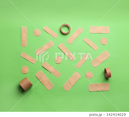 Different types of sticking plasters on green background, flat lay 142414029