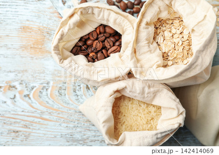 Cotton eco bags with cereals and coffee beans on wooden table, flat lay 142414069