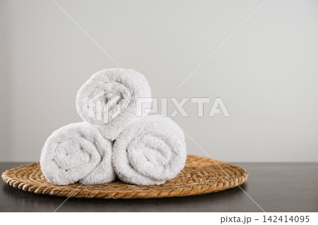 Clean rolled bath towels and wicker mat on dark grey table. Space for text Clean rolled bath towels and wicker mat on dark grey table. Space for text 142414095