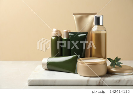 Different cosmetic products on white table against beige background Different cosmetic products on white table against beige background 142414136