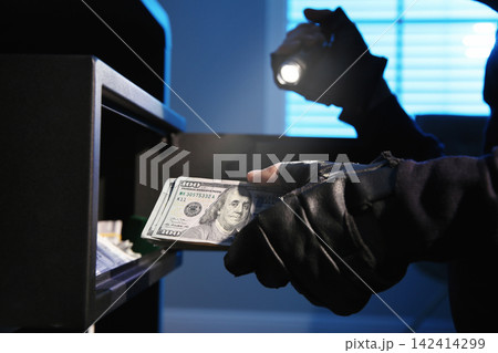 Thief taking money out of steel safe indoors at night, closeup Thief taking money out of steel safe indoors at night, closeup 142414299