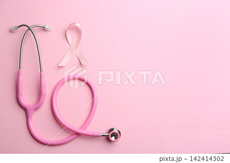 Pink ribbon as breast cancer awareness symbol and stethoscope on color background, flat lay. Space for text Pink ribbon as breast cancer awareness symbol and stethoscope on color background, flat lay. Space for text 142414302