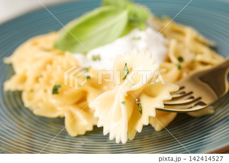 Tasty farfalle pasta with herbs on fork, closeup Tasty farfalle pasta with herbs on fork, closeup 142414527