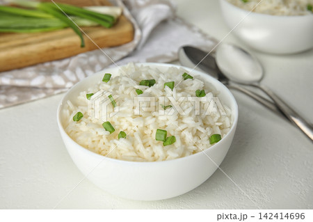 Bowl with tasty cooked rice on white table Bowl with tasty cooked rice on white table 142414696