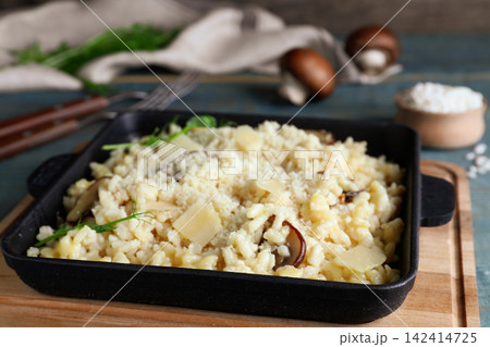 Delicious risotto with cheese and mushrooms on wooden board, closeup Delicious risotto with cheese and mushrooms on wooden board, closeup 142414725