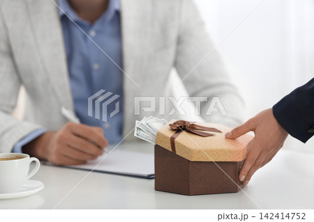 Woman giving bribe to man at table in office, closeup 142414752