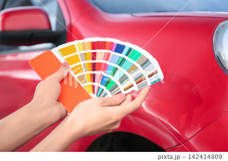 Woman with palette samples choosing color for painting car, closeup 142414809