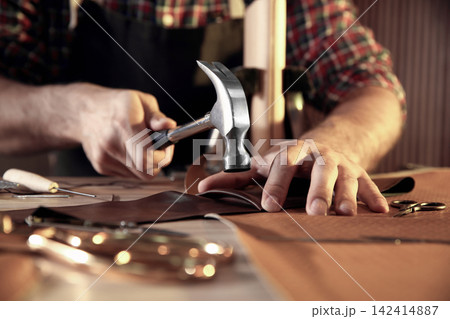 Man working with piece of leather at table, closeup Man working with piece of leather at table, closeup 142414887