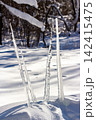 Sharp, gleaming icicle daggers dramatically pierce soft, fresh snow, creating an unusual, stark winter backdrop under clear, bright sun 142415475