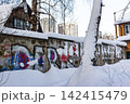 Urban decay meets winter wonderland with vibrant graffiti on a snow-covered concrete wall juxtaposed against modern high-rises 142415479