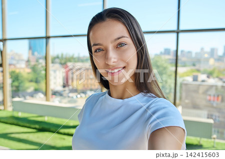 Young smiling female student looking at camera while taking selfie photo Young smiling female student looking at camera while taking selfie photo 142415603