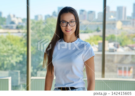 Young smiling female student in eyeglasses looking directly at camera Young smiling female student in eyeglasses looking directly at camera 142415605