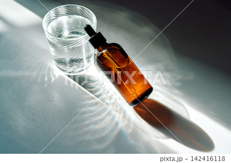 Skincare oil dropper bottle and glass of water 142416118