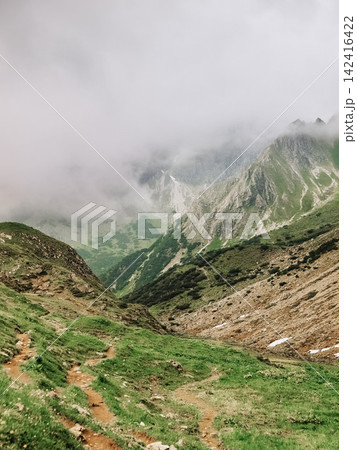 Dramatic alpine panorama from the Mindelheim Via Ferrata in the Allgaeu Alps, Germany, partially snow covered mountain slopes and rugged peaks emerging through clouds, cinematic adventure travel 142416422