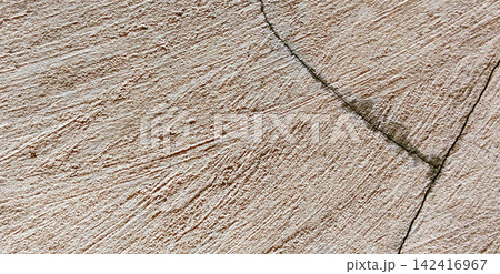 Textured beige concrete wall with diagonal cracks Textured beige concrete wall with diagonal cracks 142416967