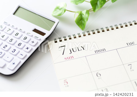 7月のカレンダーと白い電卓 7月のカレンダーと白い電卓 142420231