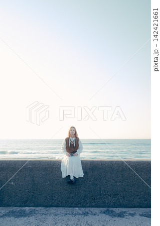 海を背景にフィルムカメラを構える若い女性 海を背景にフィルムカメラを構える若い女性 142421661