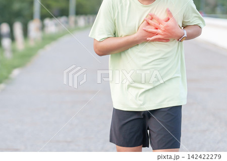 Adult runner suffering from acute chest pain and heart attack during running. man holding chest due to cardiac arrest, angina or heart disease. Sports medical and healthcare concept Adult runner suffering from acute chest pain and heart attack during running. man holding chest due to cardiac arrest, angina or heart disease. Sports medical and healthcare concept 142422279