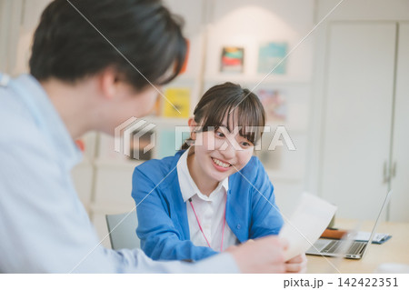 書類について確認しながら笑顔で話す女子社員のオフィスシーン 書類について確認しながら笑顔で話す女子社員のオフィスシーン 142422351